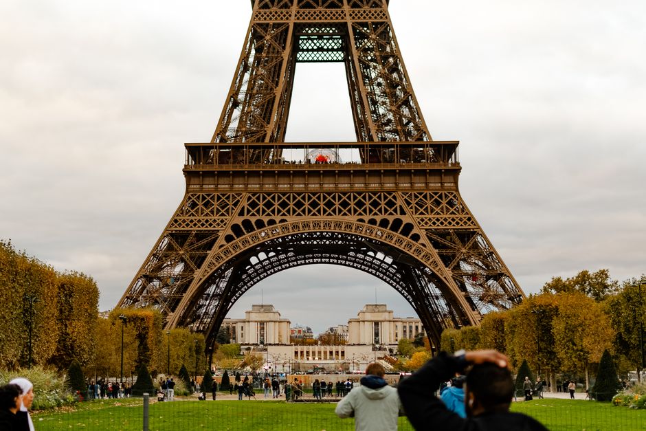 Open suitcase with travel essentials for a trip to France, with Eiffel Tower in background
