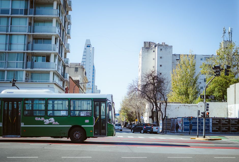 A bustling street scene in Buenos Aires, Argentina, featuring a colorful local bus and people using public transport.
