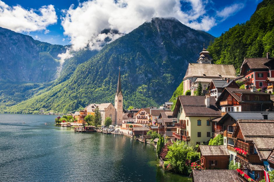 Panoramic view of a charming Austrian town with mountains and a train in the distance, illustrating travel in Austria