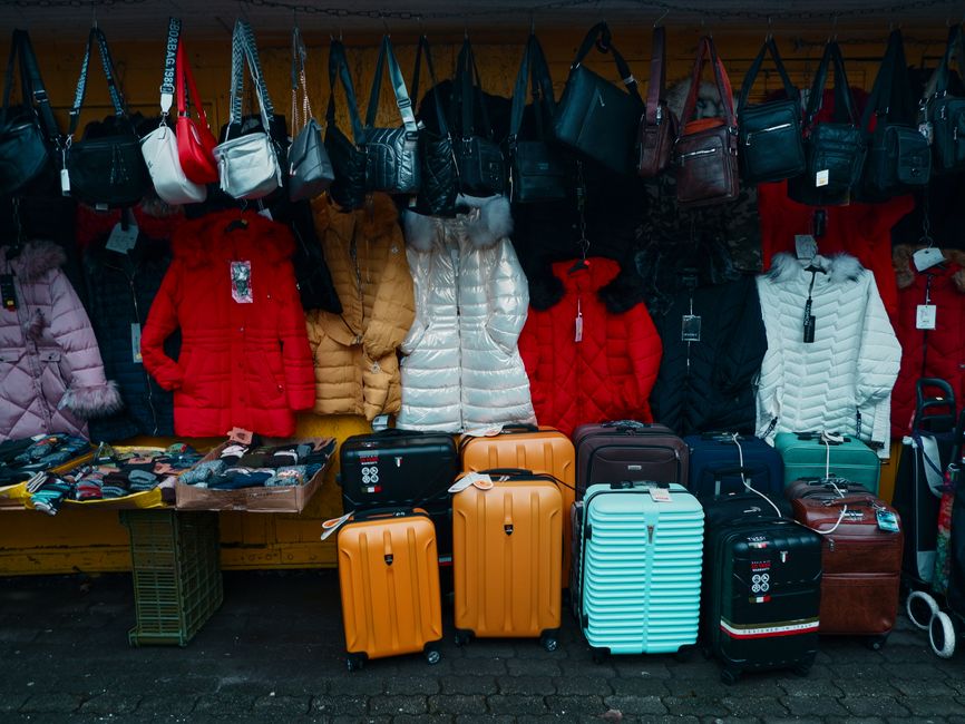 A neatly packed suitcase with travel essentials for a trip to Bulgaria, including clothes, adapter, and a map.
