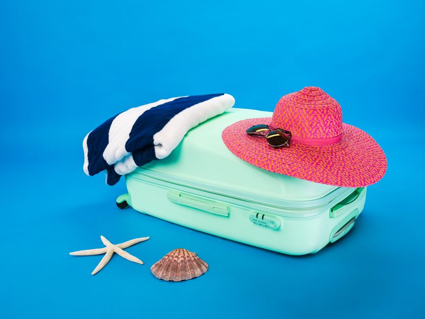 A neatly organized suitcase with essentials for a trip to Croatia, including swimwear, sunscreen, and walking shoes.