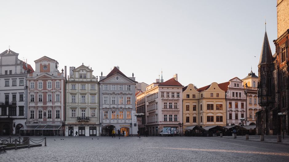 Panoramic view of Prague Old Town Square with Tyn Church and Astronomical Clock at sunset.