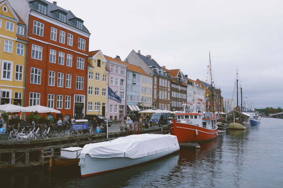 Colorful buildings along a canal in Copenhagen, Denmark, with a cozy hotel in the foreground