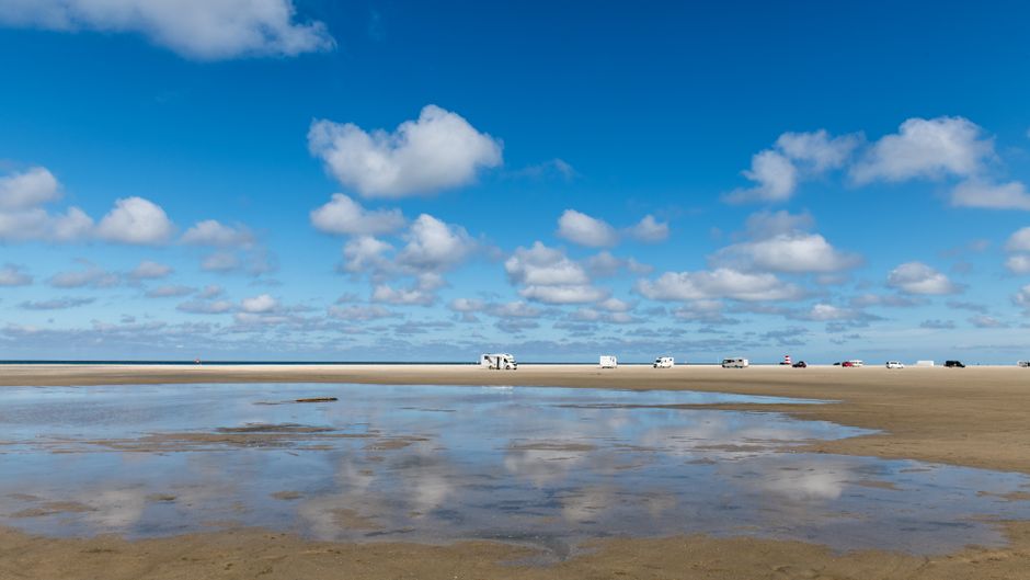 A car driving on a scenic coastal road in Denmark with blue skies