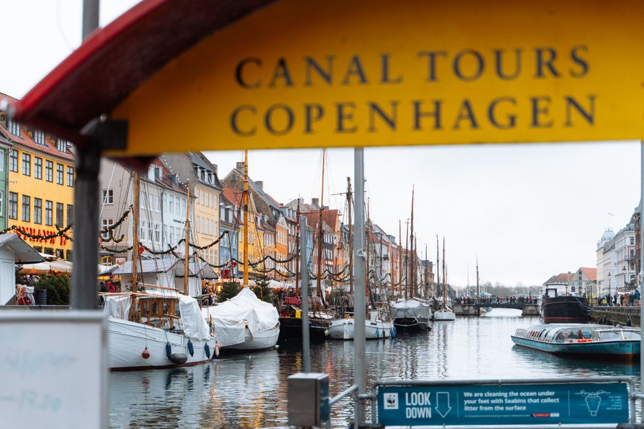 Colorful buildings along Nyhavn canal with tour boats in Copenhagen, Denmark