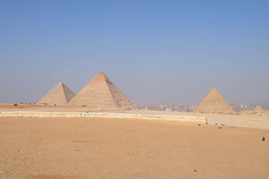 A rental car, possibly a Kia Picanto, parked near the Giza Pyramids in Egypt, ready for a road trip adventure.
