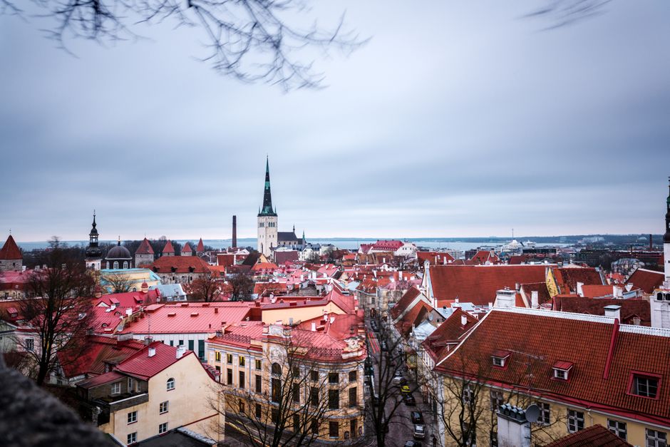 A historic tram moving through Tallinn Old Town, Estonia, with people navigating the streets.
