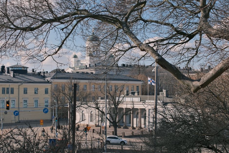A modern tram moving through a bustling street in Helsinki, Finland, with historic architecture in the background, symbolizing urban travel.