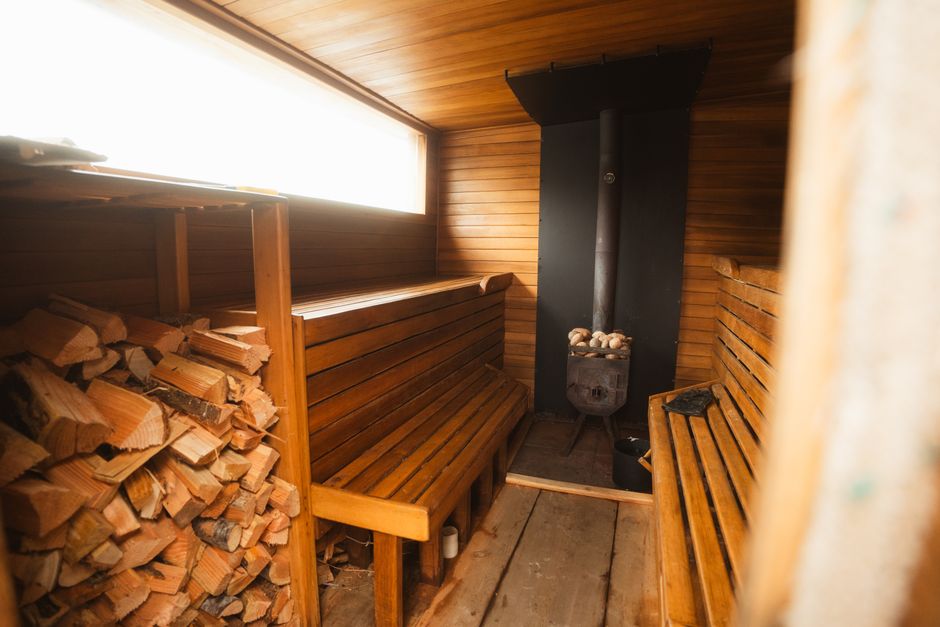 Interior of a traditional Finnish sauna with wooden benches and a stove, inviting travelers to experience Finland's culture.