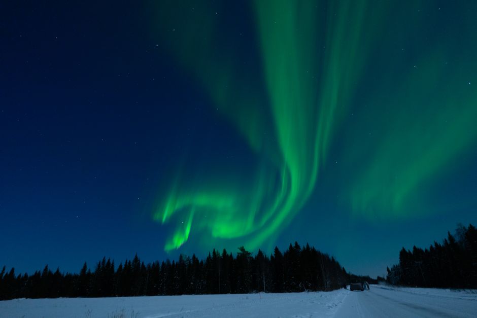 Stunning aurora borealis over a snowy Finnish winter landscape, highlighting the need for warm packing