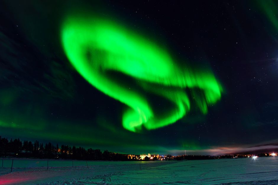 Spectacular Northern Lights dancing over a snowy forest in Lapland, Finland