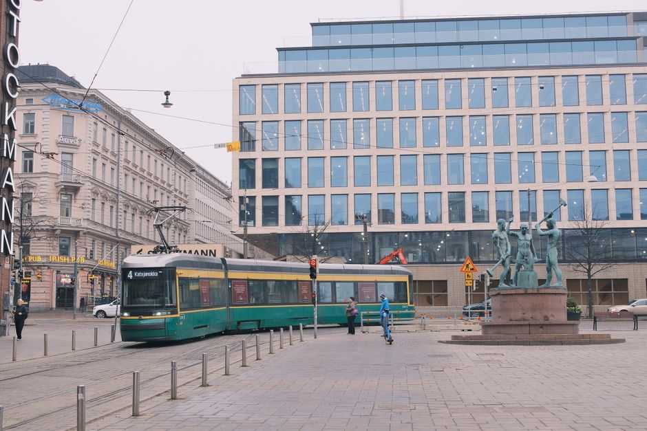 A modern tram moving through a bustling street in Helsinki, Finland, showcasing efficient public transport.