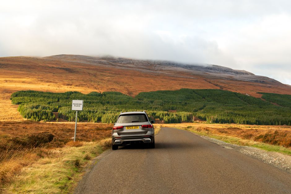 Car driving on the left side of a scenic road in the British countryside