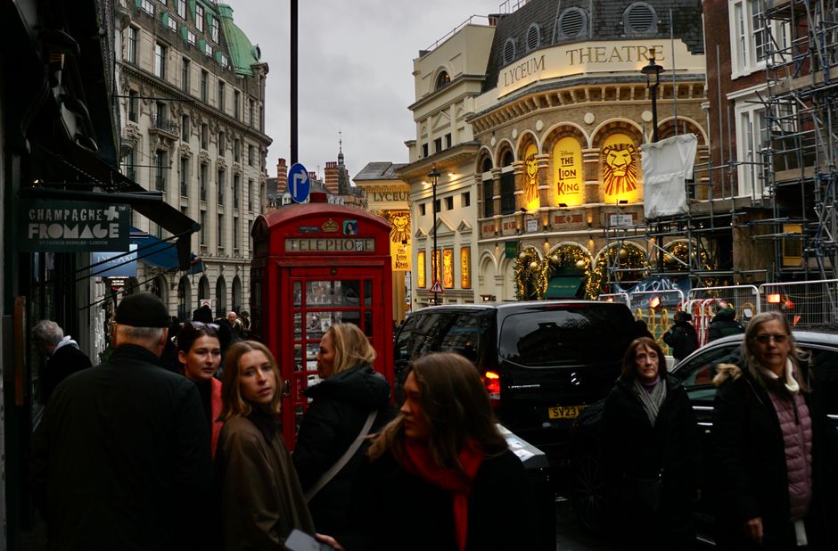 Tourist using smartphone with London cityscape in background, symbolizing internet access in Great Britain