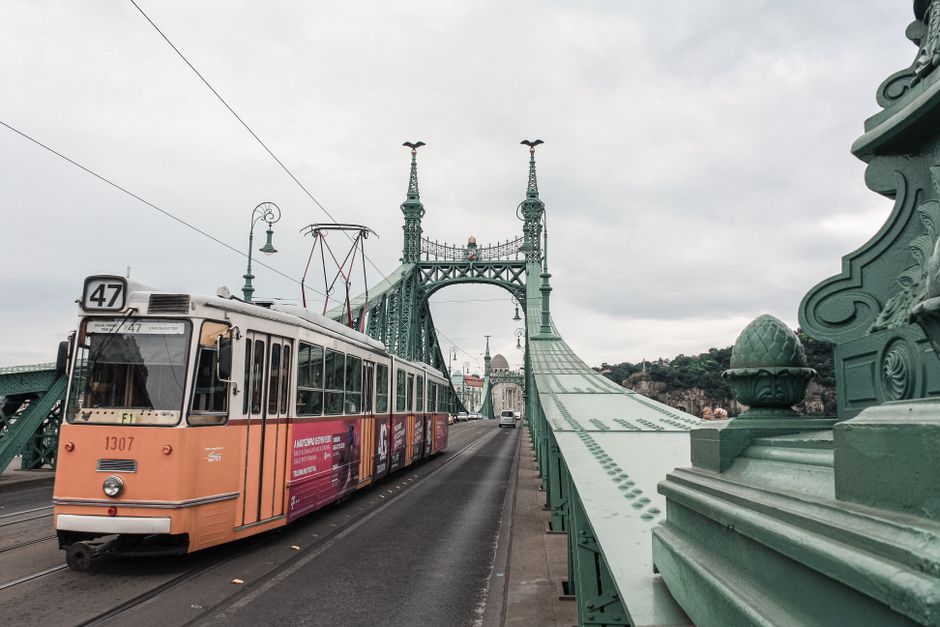 A yellow tram moving through a historic street in Budapest, Hungary, showcasing efficient public transport.