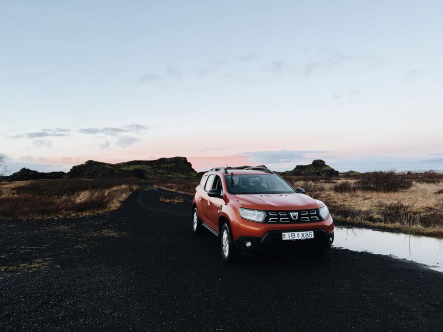 A car driving on a scenic road through the volcanic landscape of Iceland