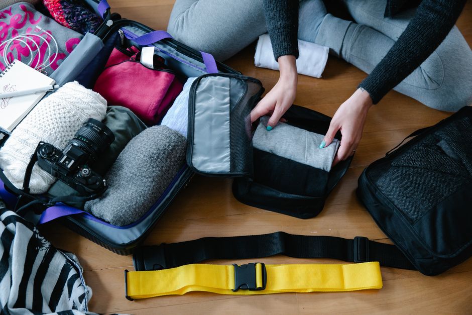 A traveler packing a suitcase with lightweight clothes and travel essentials for a trip to India