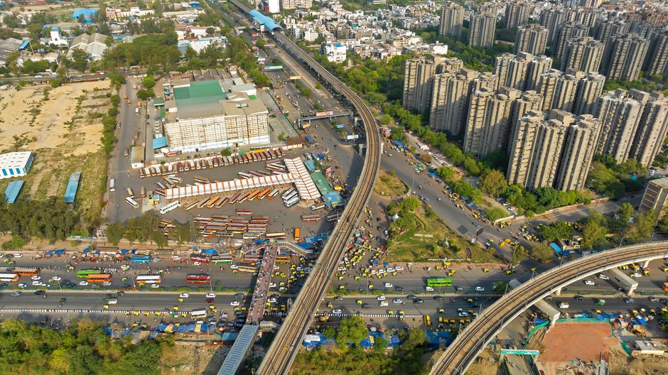 Bustling transport hub in India with various modes of transport like auto-rickshaws and cars