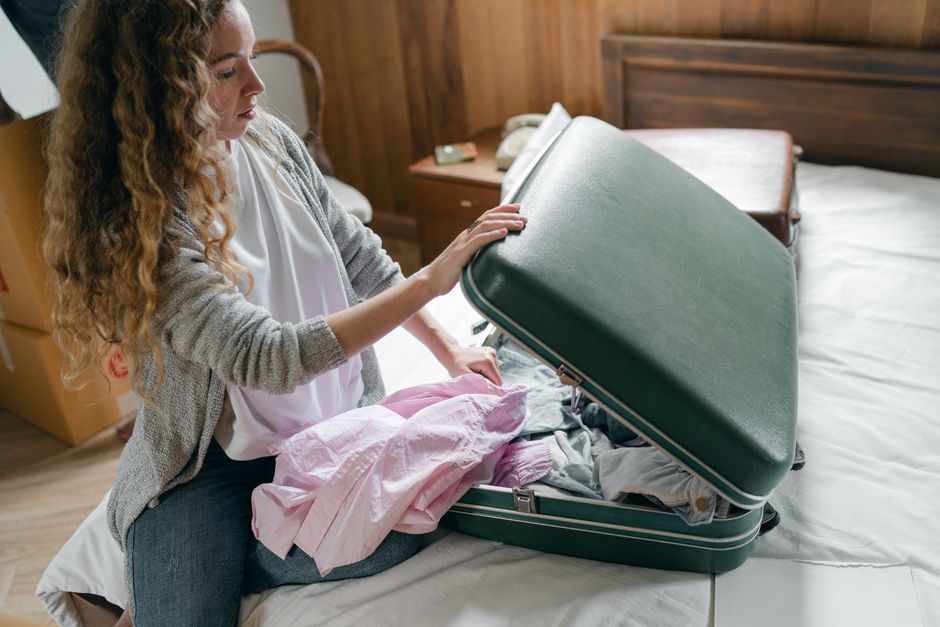 Traveler packing a suitcase with waterproof jacket and walking boots for a trip to Ireland