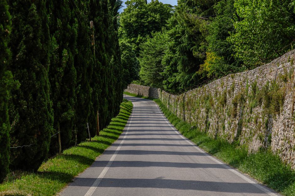 A compact car driving on a scenic road through the Italian countryside with rolling hills
