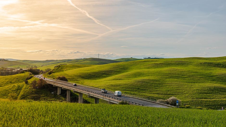 Sunny Italian landscape with rolling hills and cypress trees, showcasing beautiful weather