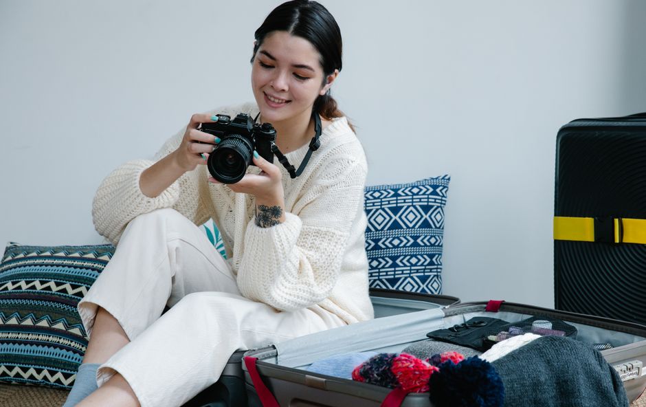 Traveler packing a suitcase with items for a trip to Japan, including clothes and electronics