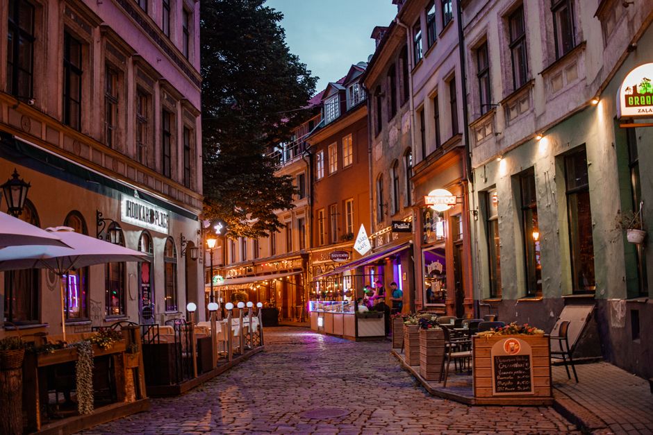 Traveler using a smartphone in Riga, Latvia, with historic buildings in the background