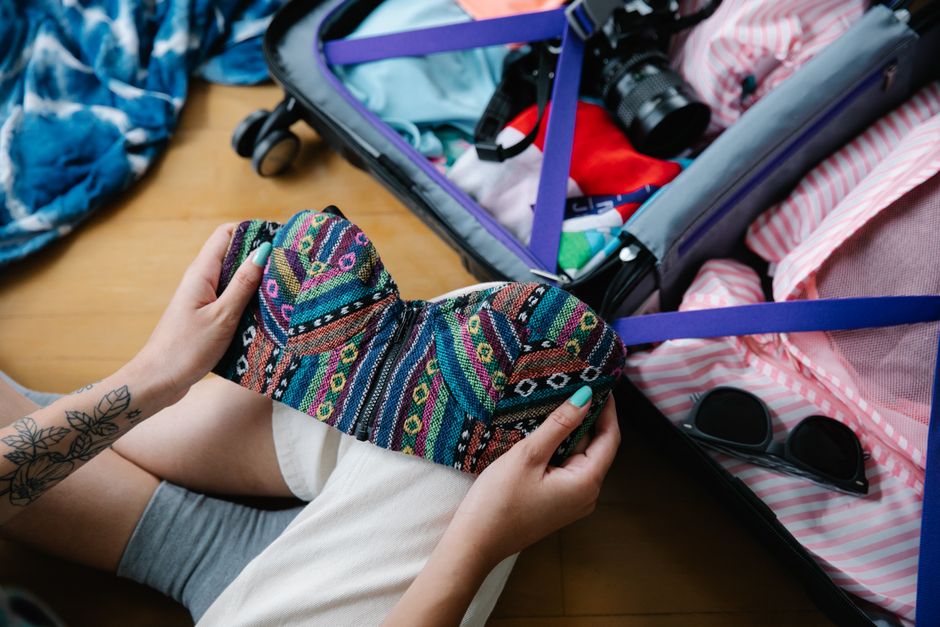 Open suitcase with travel essentials for a trip to Latvia, including layers and an adapter