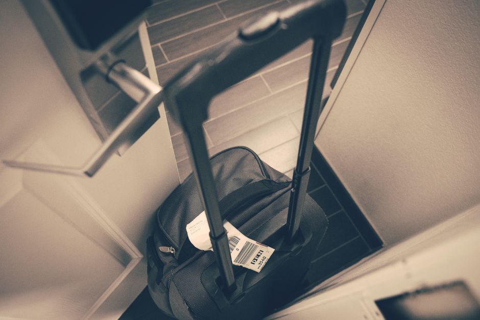 A neatly packed suitcase with travel essentials for a trip to Lithuania, including a power adapter and rain jacket.
