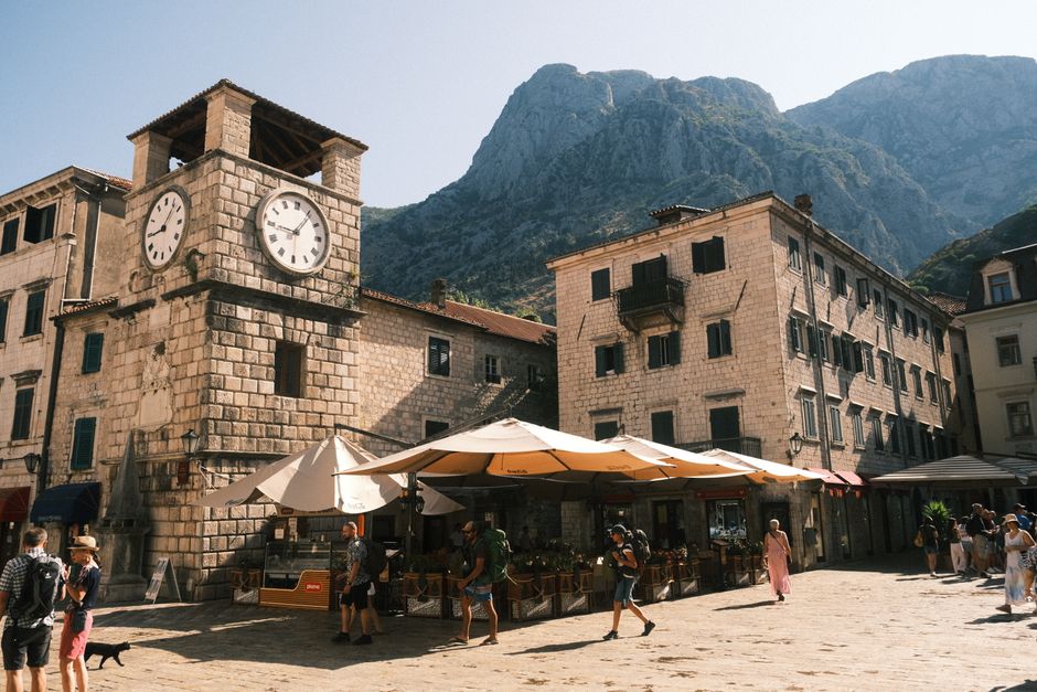 A charming street cafe in Kotor, Montenegro, with people enjoying coffee and pastries, illustrating daily living costs.