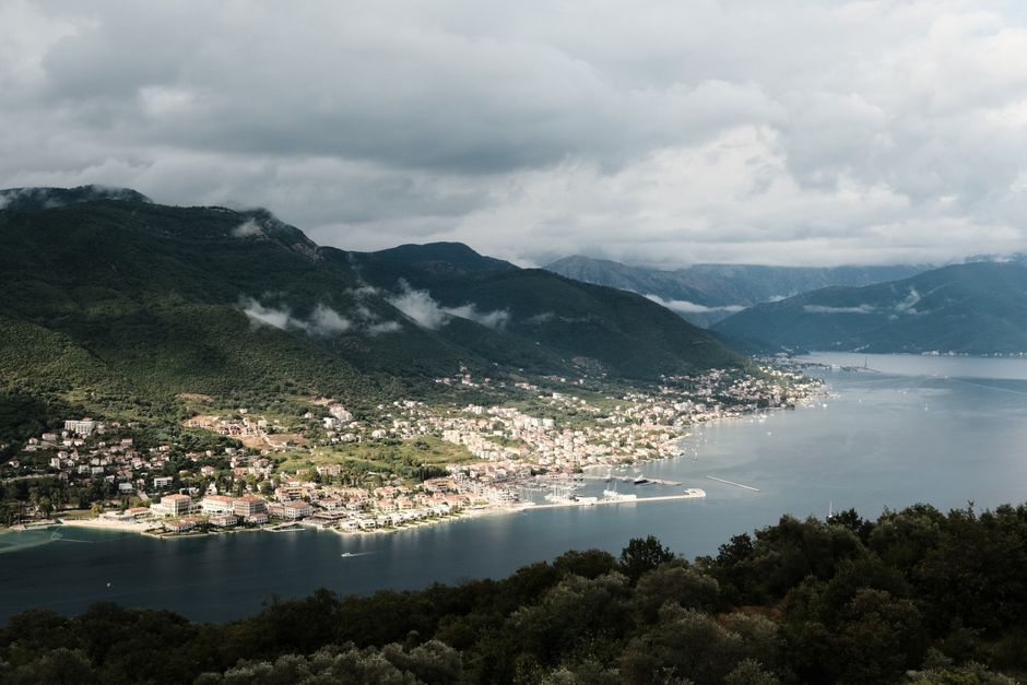 Panoramic view of Kotor Bay, Montenegro, with historic towns nestled along the coastline and dramatic mountains in the background