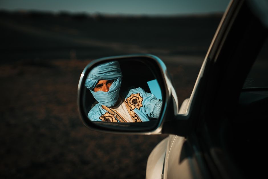 A rental car driving on a scenic road through the Moroccan desert landscape