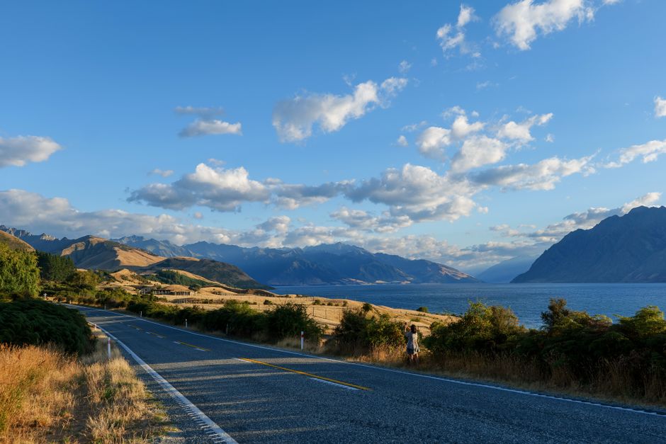Traveler using a smartphone with a stunning New Zealand mountain and lake backdrop