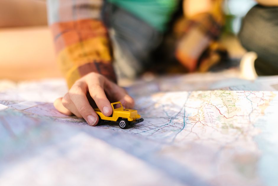 Traveler looking at a map of New Zealand with stunning landscapes in the background