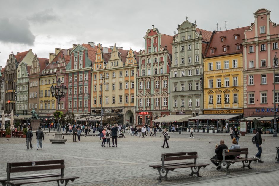 Vibrant Main Market Square in Kraków, Poland, with historic buildings and people enjoying the atmosphere, symbolizing affordable travel