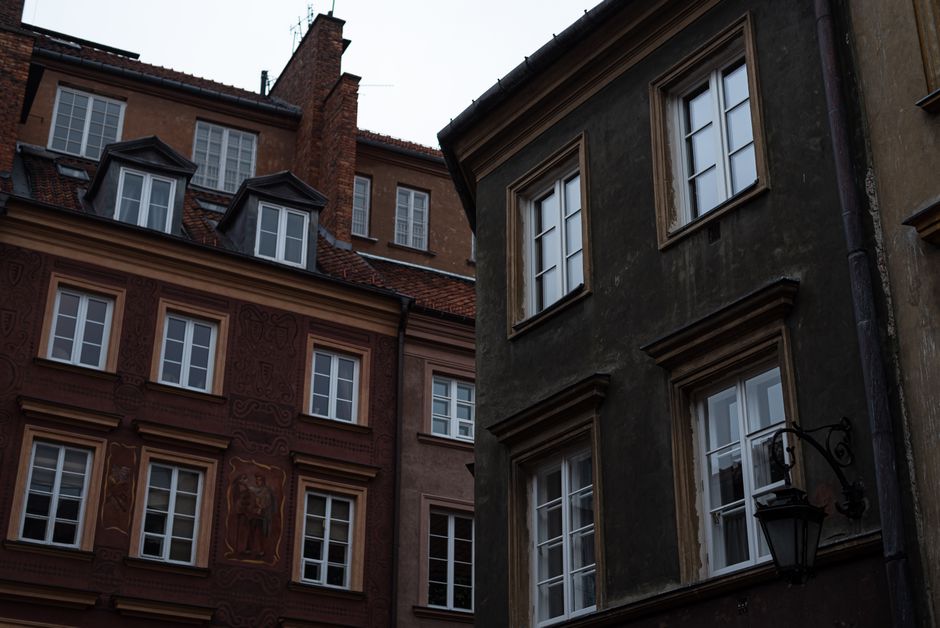 Charming Old Town square in Warsaw, Poland, bustling with people at sunset, showcasing historic architecture.