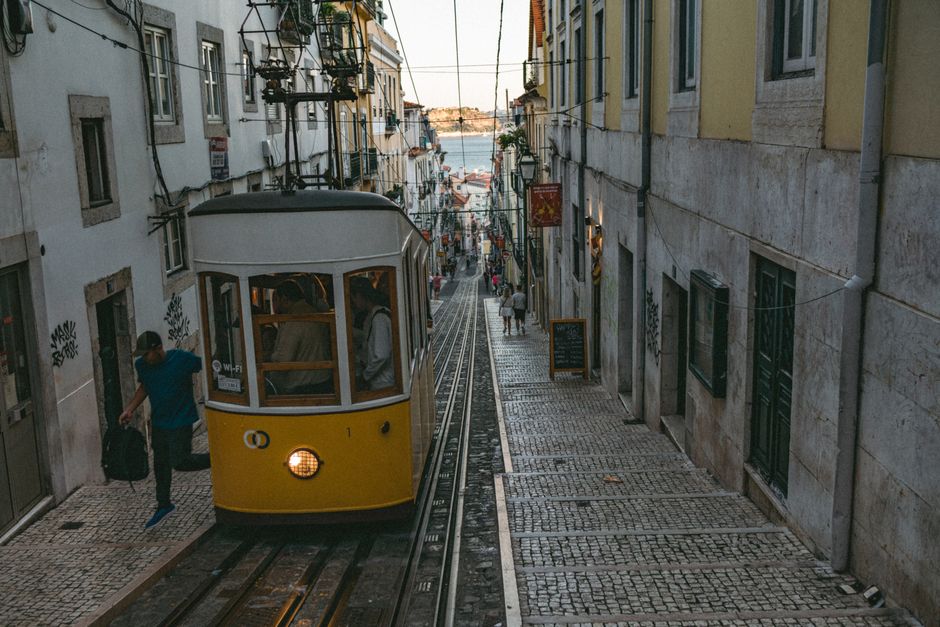 Historic yellow tram winding through a narrow street in Lisbon, Portugal