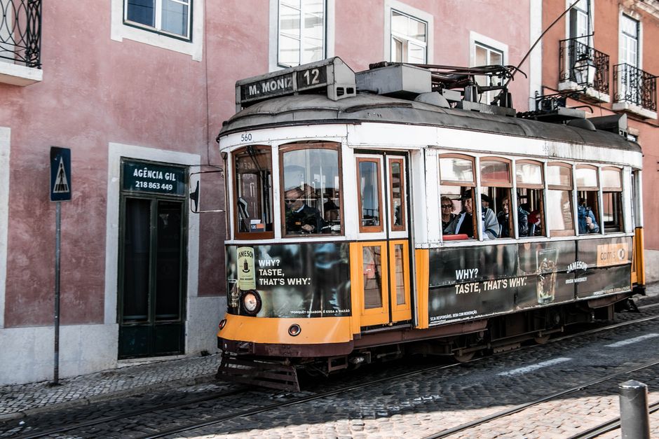 Iconic yellow tram winding through a historic street in Lisbon, Portugal