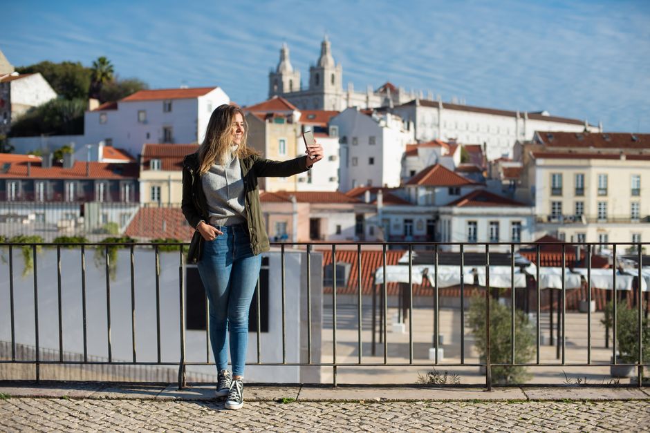 Tourist happily using a smartphone with a Portuguese SIM card in Lisbon
