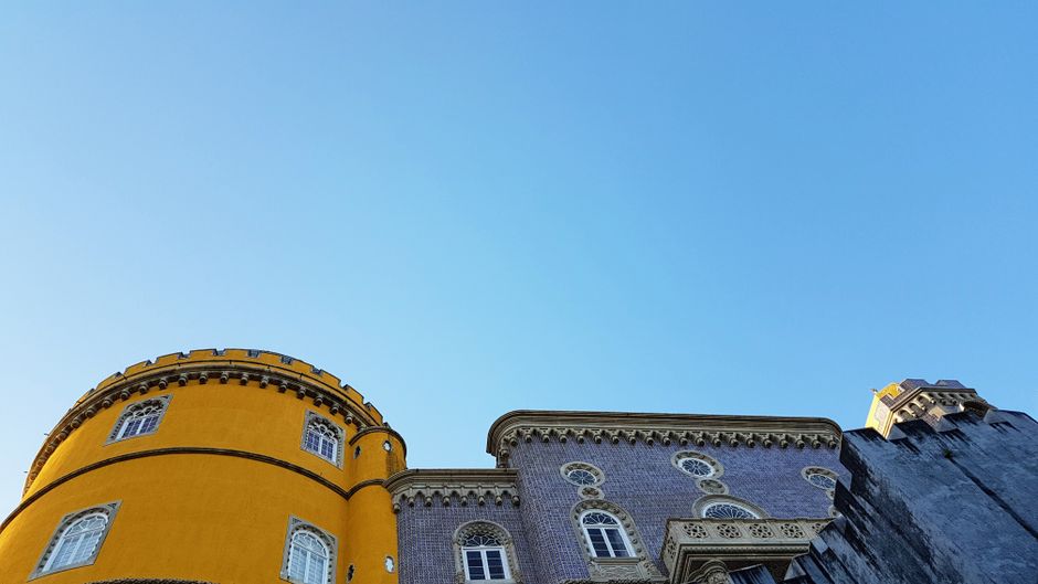 Colorful Pena Palace in Sintra, Portugal, surrounded by lush greenery, a popular tour destination.