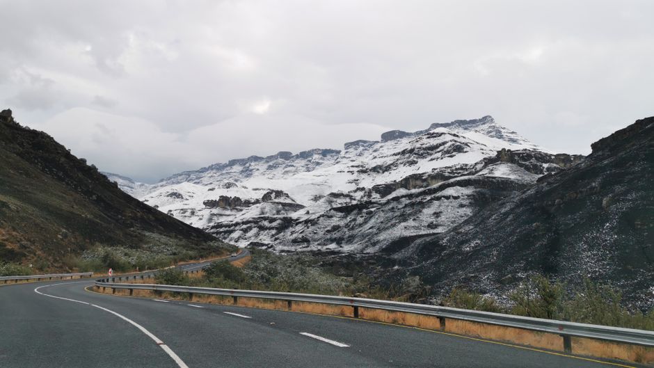 A car driving on a scenic road through the mountains in South Africa, illustrating a road trip adventure.