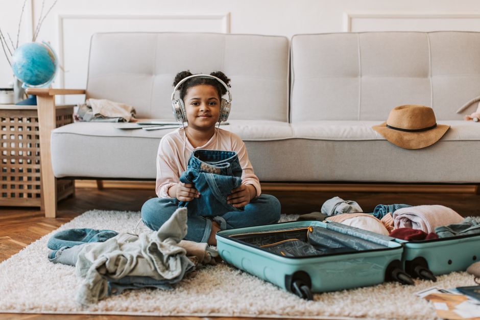 A traveler packing a suitcase with a safari hat and binoculars for a trip to South Africa