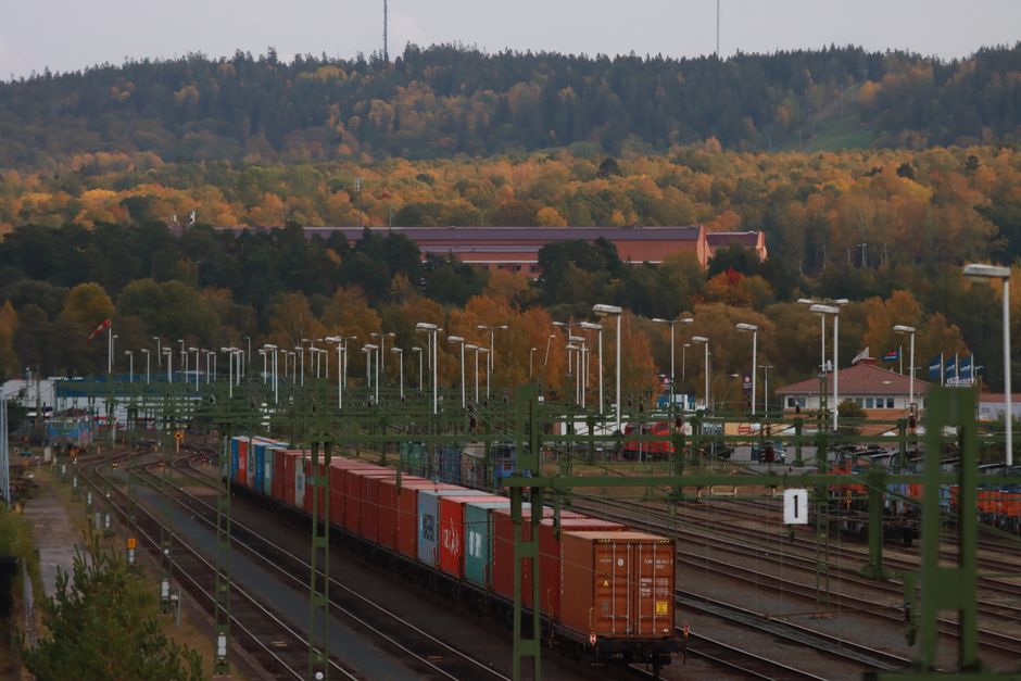 A modern SJ train speeding through a picturesque Swedish landscape during autumn