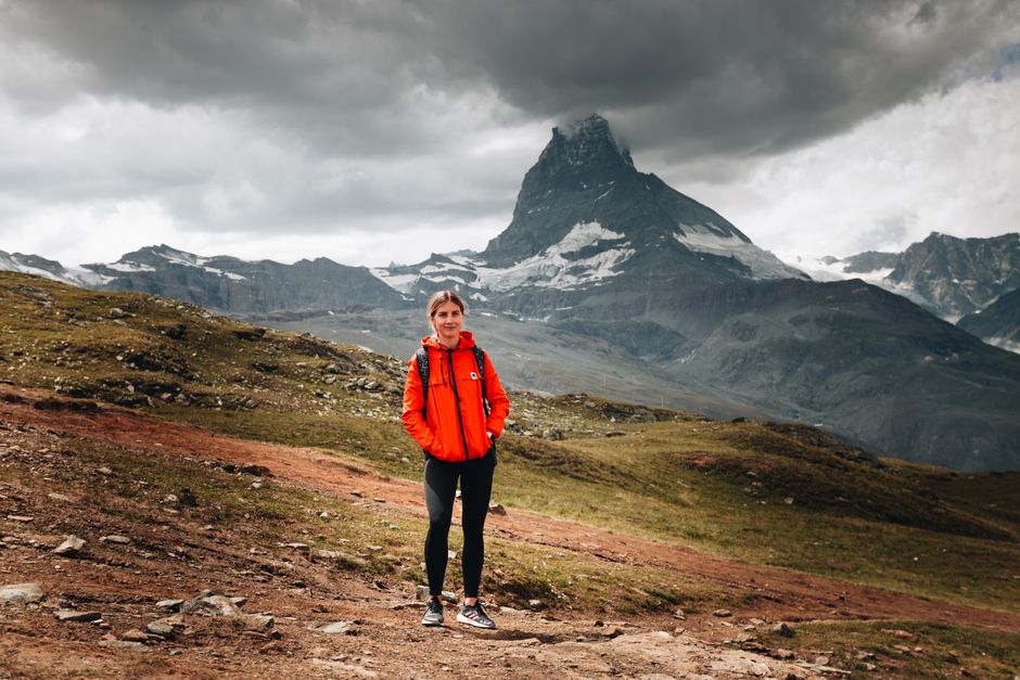 Hiker with a backpack enjoying panoramic views of the Swiss Alps, showcasing essential outdoor gear for Switzerland.