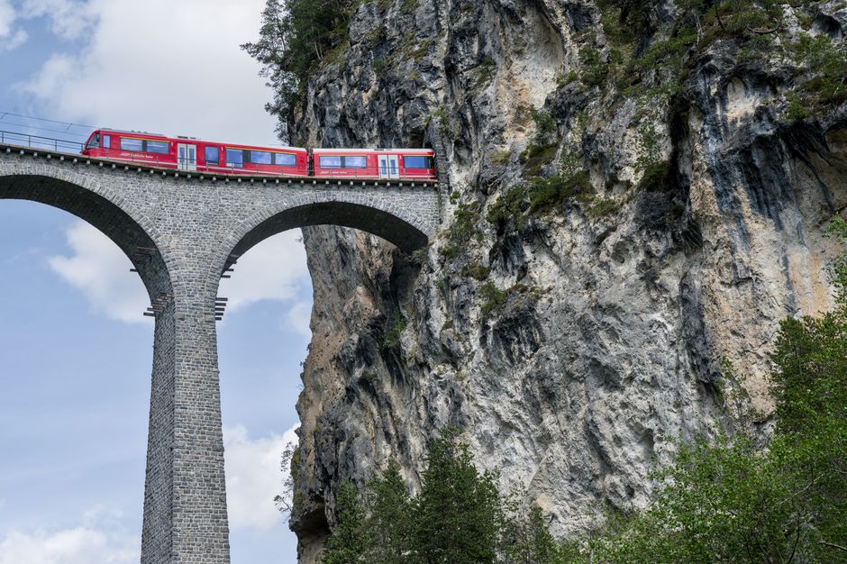 Modern Swiss train traveling through a scenic mountain valley in Switzerland