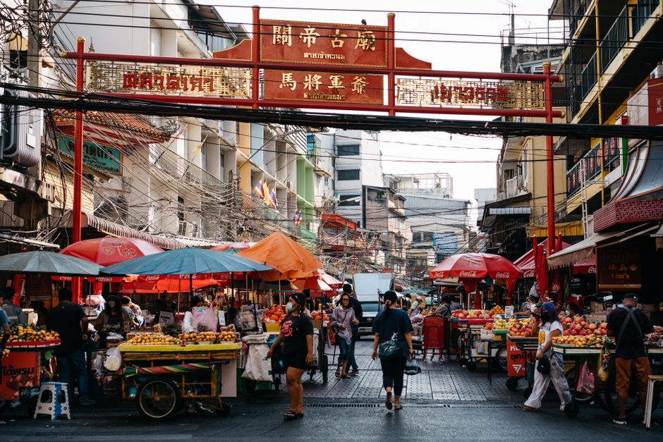 A bustling night market scene in Bangkok, Thailand, with food stalls and shoppers