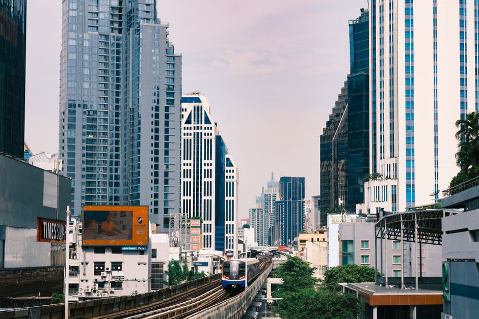 BTS Skytrain moving through a modern Bangkok cityscape at sunset in Thailand