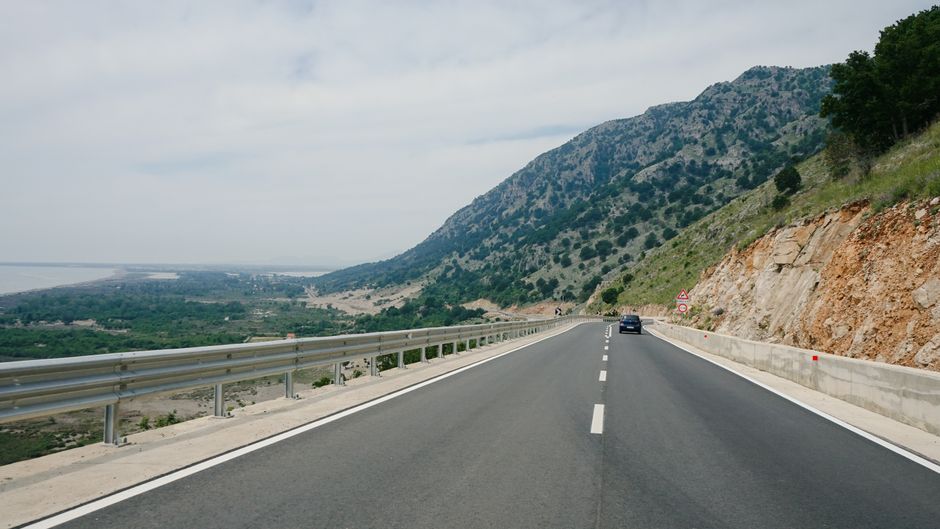 A car driving along a scenic coastal road in Turkey with the Mediterranean Sea in the background