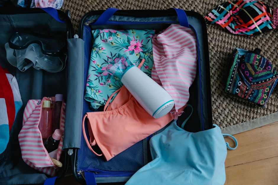 Open suitcase with essential items for a trip to Turkey, including a scarf and travel adapter