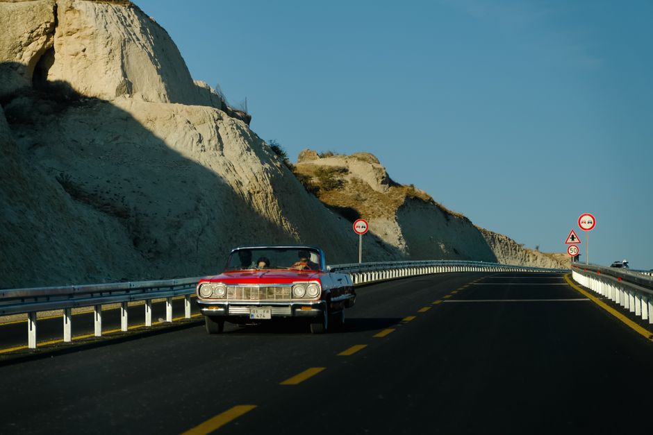 Red convertible driving on a scenic highway in the American Southwest, symbolizing a USA road trip